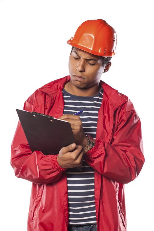 A worker wearing a hard hat writes a near-miss report