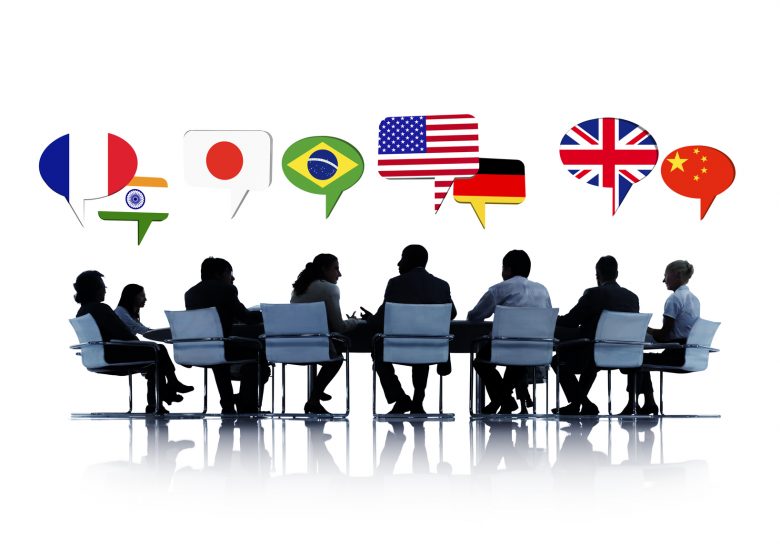 Businesspeople sit around a boardroom table speaking different languages