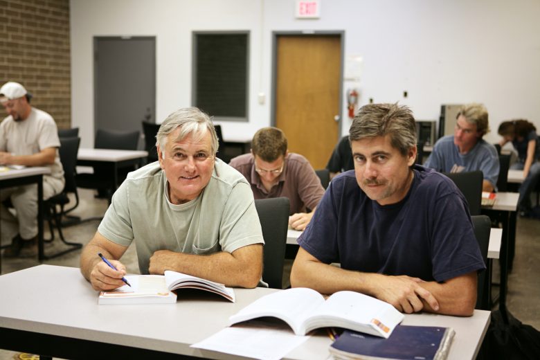 Two adult men sitting in a classroom for training