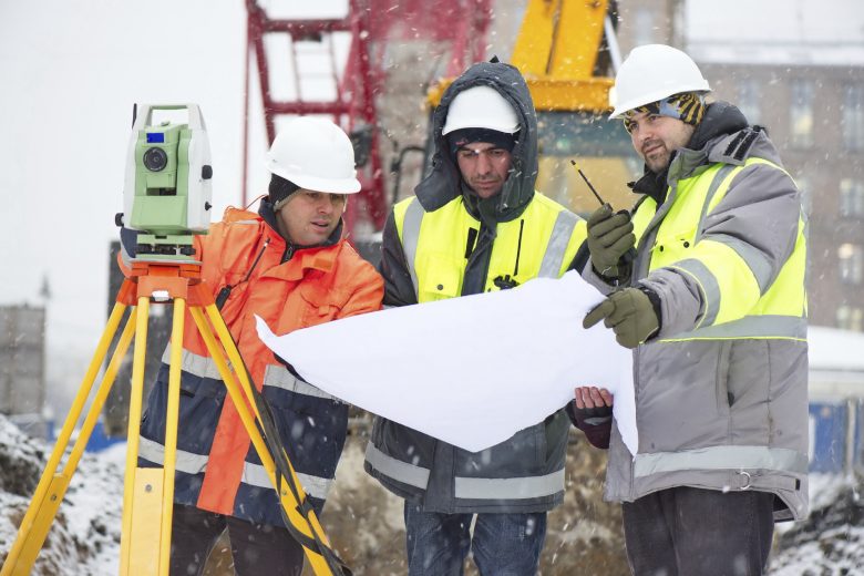 Winter construction site, workers look at construction plans