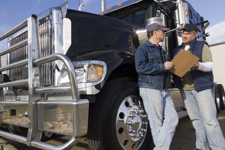 Two men discuss safety outside transport truck