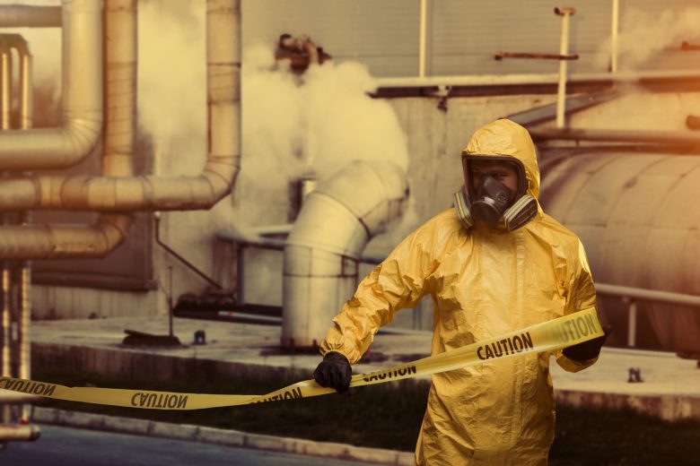 Man working in a factory in protective bio hazard work wear with caution cordon tape