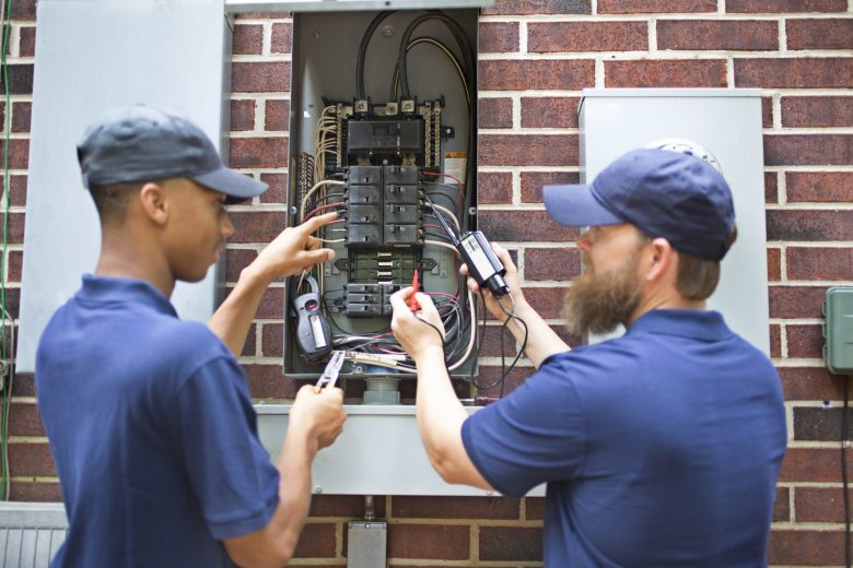 Two electricians checking an electrical panel