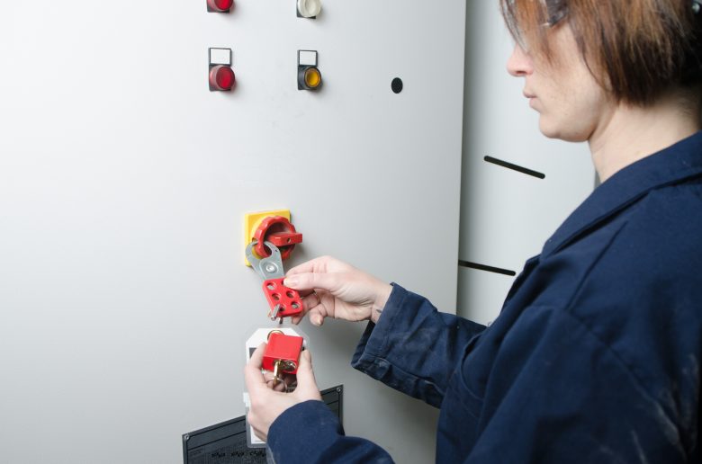 Woman performing lockout/tagout on electrical box