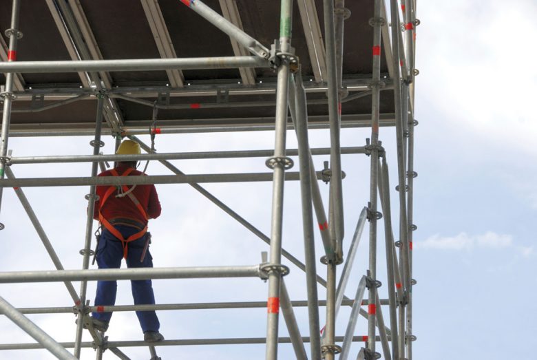 Construction worker working at heights on construction scaffolding