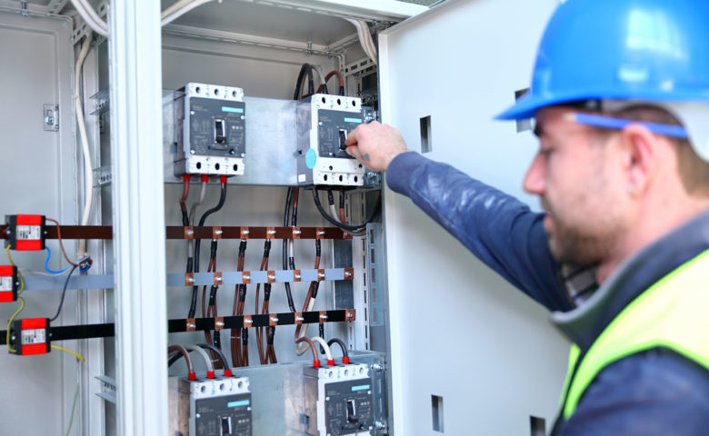 Electrician working with industrial circuit breakers