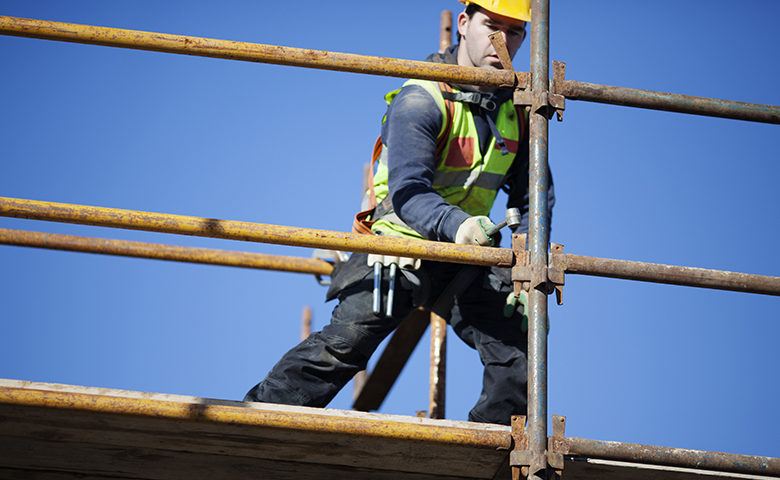 A construction worker setting up scaffolding