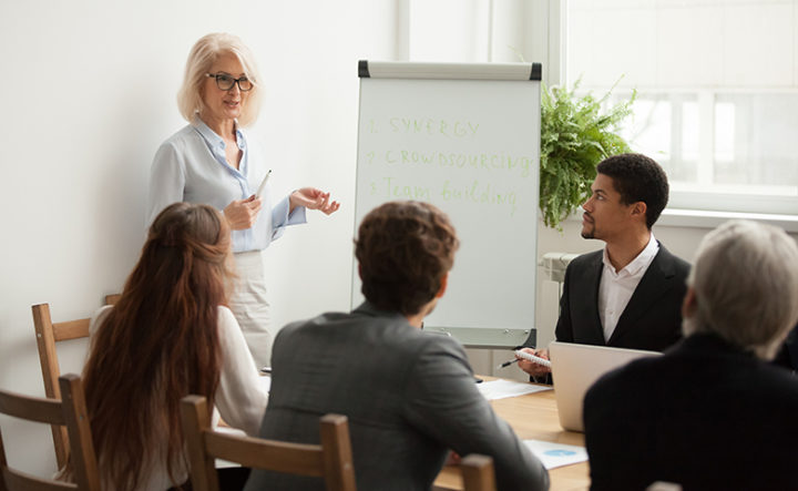 Aged attractive businesswoman giving presentation at corporate team meeting