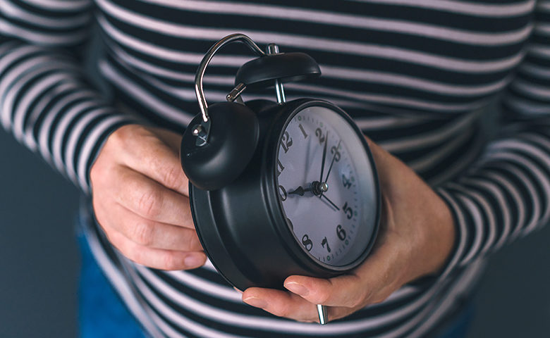 Woman winding retro alarm clock