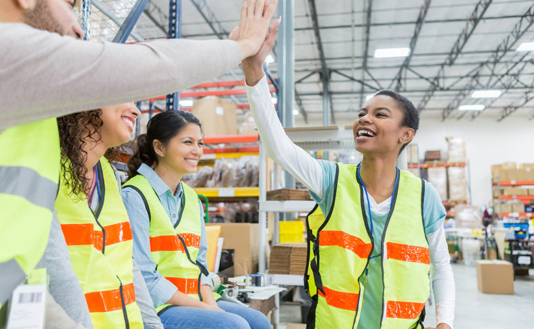 Warehouse employee receives congratulations during team meeting