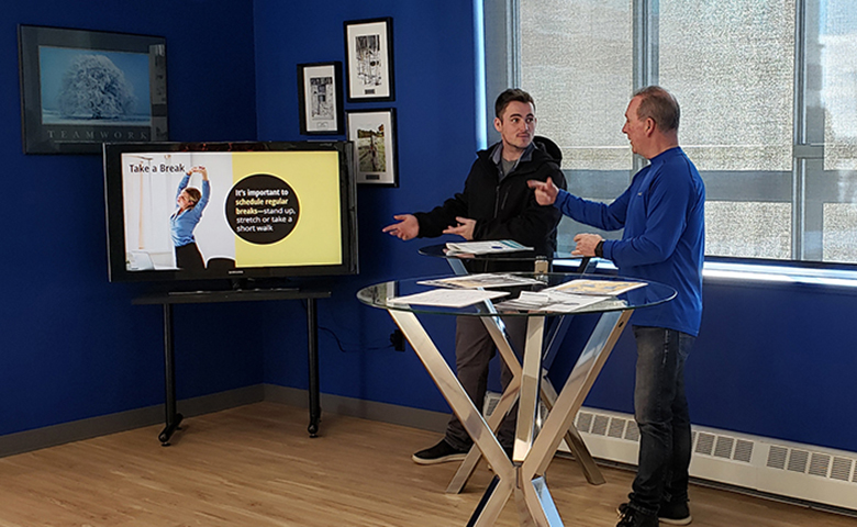 Christien and Paul talking near the TV at a bistro table