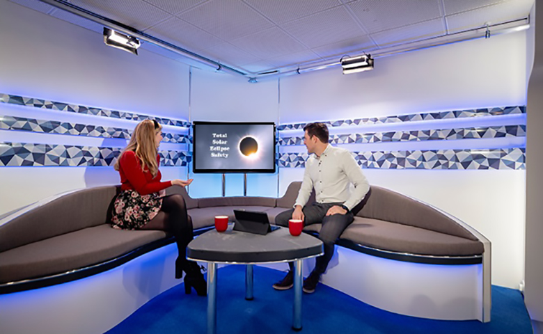 Two workers taking in a digital display presentation in their breakroom